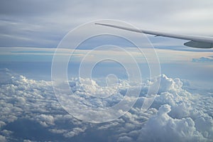 View of beautiful cloudscape with shades of blue sky background from flying plane window with airplane wing