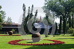 view of a beautiful decorated garden in front of bran castle in romania with wooden shed, giant vase and artificial pond