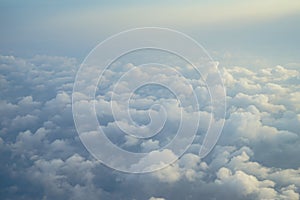 View of beautiful dreamy fluffy abstract white cloud with blue sky and sunrise light background from airplane window