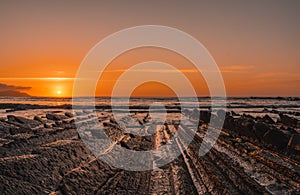 View of the beautiful orange sunset on the flysch of the Sakoneta beach