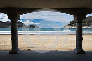 View on beautiful sandy beach la concha of san sebastian through arch arcade, basque country, spain