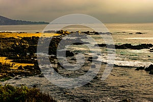 view of a beautiful seascape at sunset where you can see the waves of the sea breaking on the rocks in central Chile