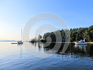 A view of a beautiful secluded bay during a beautiful sunny evening.  The water is calm, a few boats are anchored,