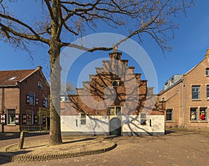 View of a beautiful stepped gable house in a Dutch village, photographed in early spring, the first spring day, with trees that st