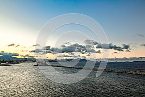 View of beautiful sunset with pepper clouds, sea and waves view from height. Skyline and coastline. Cargo ship enters