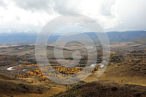 A view of a beautiful winding river flowing through a wide valley along a mountain range with snow-capped peaks