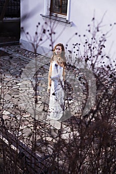 View of a beautiful young girl with a long white dress in the ga