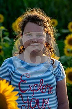 Beauty joyful young girl with sunflower enjoying nature and laughing on summer sunflower field. Sunflare, sunbeams, glow