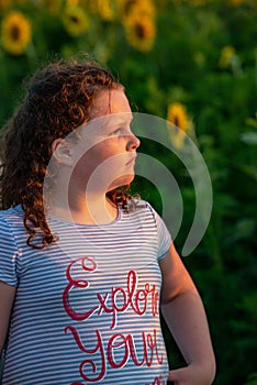 Beauty joyful young girl with sunflower enjoying nature and laughing on summer sunflower field. Sunflare, sunbeams, glow