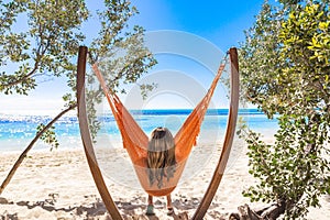 View from behind of a beautiful woman relaxing in a unique hammock with a spectacular view of the Caribbean ocean