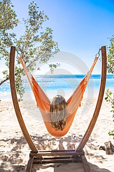 View from behind of a beautiful woman relaxing in a unique hammock with a spectacular view of the Caribbean ocean