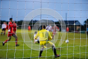 View from behind a footbal goal where the players are out of focus photo