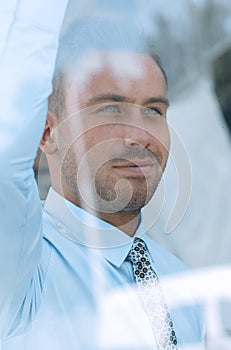 View from behind glass.confident businessman looking out the window of his office