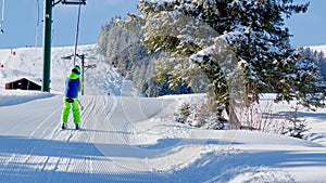 View from behind of a little boy on t-bar ski lift