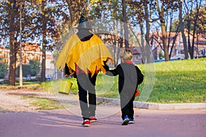 View from behind of two boys walk in Halloween costumes