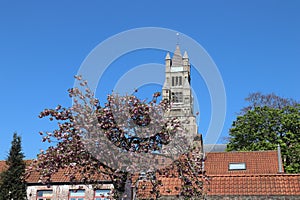 The view of the Belfort medieval bell tower Beffrey is the symbol of the city of Bruges against a bright blue sky and tile roofs