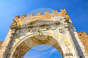 View from below of ancient brick wall and stone gate Arch of Augustus Arco di Augusto ruins in Rimini