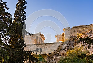 View from below and aside of temple of Athena Nike and Propylaea entrance gateway on Acropolis, Athens, Greece against blue sky