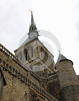 view from below of bell tower with statue of the archangel Michael in the Mont Saint Michel Abbey in France