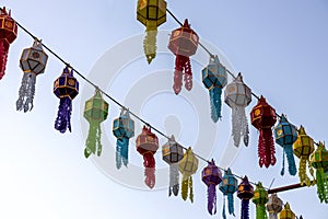 A view from below of colorful lantern flags hanging on strings of lights