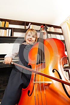 View from below of girl in dress playing on cello