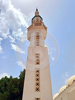 View from below of mosque minaret in Dahab on the Sinai Peninsula. Minaret detail under blue sky. Islamic culture and religions.