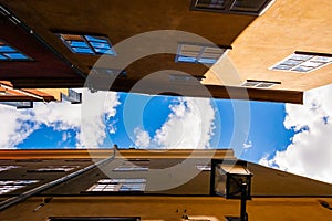 View from below on the roofs of a cozy narrow medieval street yellow orange red buildings facades in Gamla stan, Old Town of