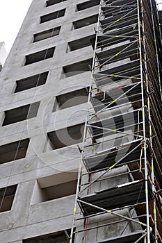 View from below on scaffold placed against unfinished edifice, new residential building under construction