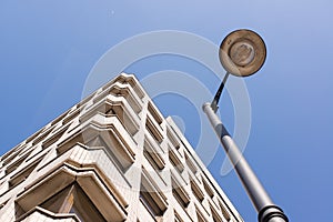 View from below of a street lamp with block of flats and blue sk