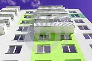 View from below upwards on blue sky and multi-storey house.