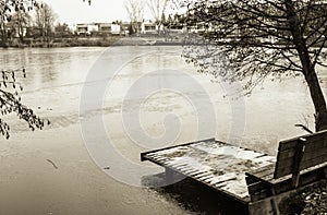 View on bench and footbridge in winter season in black and white sepia, ljubljana, slovenia