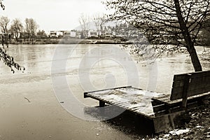 View on bench and footbridge in winter season in black and white sepia, ljubljana, slovenia