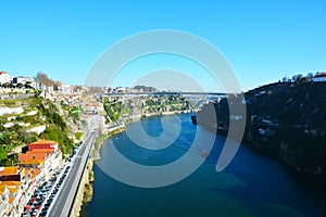 View of the bend of the Duoro River with a motor ship and houses standing on the banks of the embankment