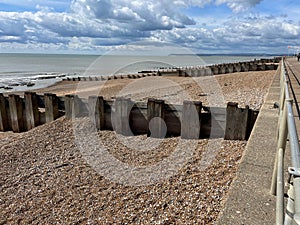 View of Bexhill on Sea seafront with groins and railing with promenade looking towards iconic Beach Head headland