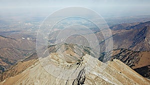 View from the Big Almaty Peak to the city of Almaty. Stone rock, blue sky, clouds and dark smog.