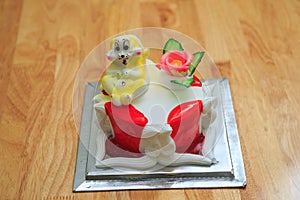 view of big light birthday cake with rabbit on wooden table