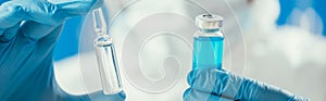 View of biochemist holding glass container with blue liquid and ampule