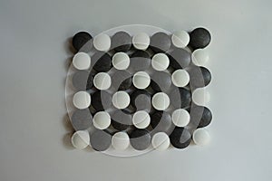 View of Black and white pills in shape of checkerboard from above