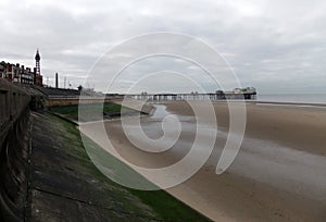 View of blackpool south pier and tower with beach at low tide with grey clouds
