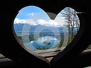 View of Bled lake and the island with the Pilgrimage church of the Assumption of Maria through a heart shaped window