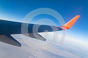 View of the blue clear sky from the height of flight above the clouds from the window of the plane in the bright sun