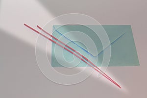 View of a blue envelope with sunbeam and red sticks on a gray background