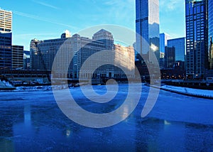 View of a blue and frigid winter morning in Chicago with reflections on a frozen Chicago River.