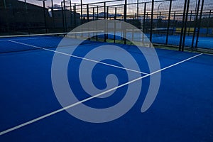 View of a blue paddle tennis court at nightfall, racket sports concept