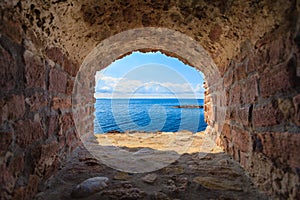 View of blue sea seascape from hole window frame in old stone wall