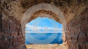 View of blue sea seascape from hole window frame in old stone wall