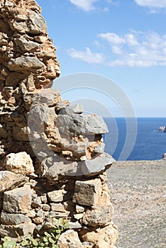 View of blue sea and sky from hole in old stonewall wall.