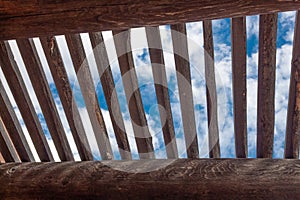 View of blue sky and clouds through lattice over exposed vigas, adobe construction