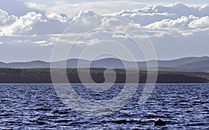 View of the blue sky over the lake with beautiful feathery and cumulonimbus clouds on a Sunny day, far away you can see