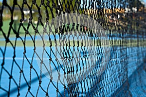 view of a blue synthetic tennis court through the central net